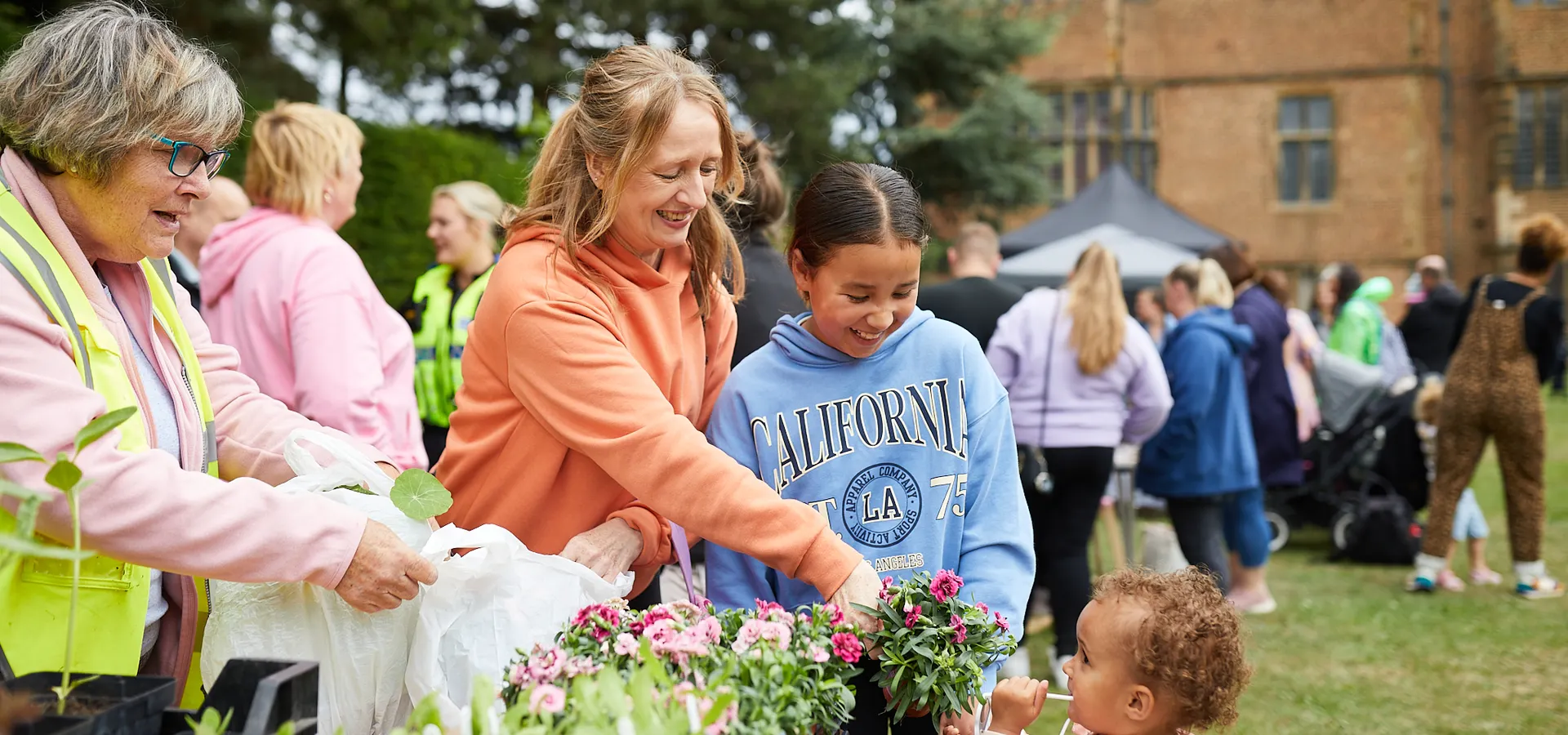 An adult and 2 children buying plants from a stall